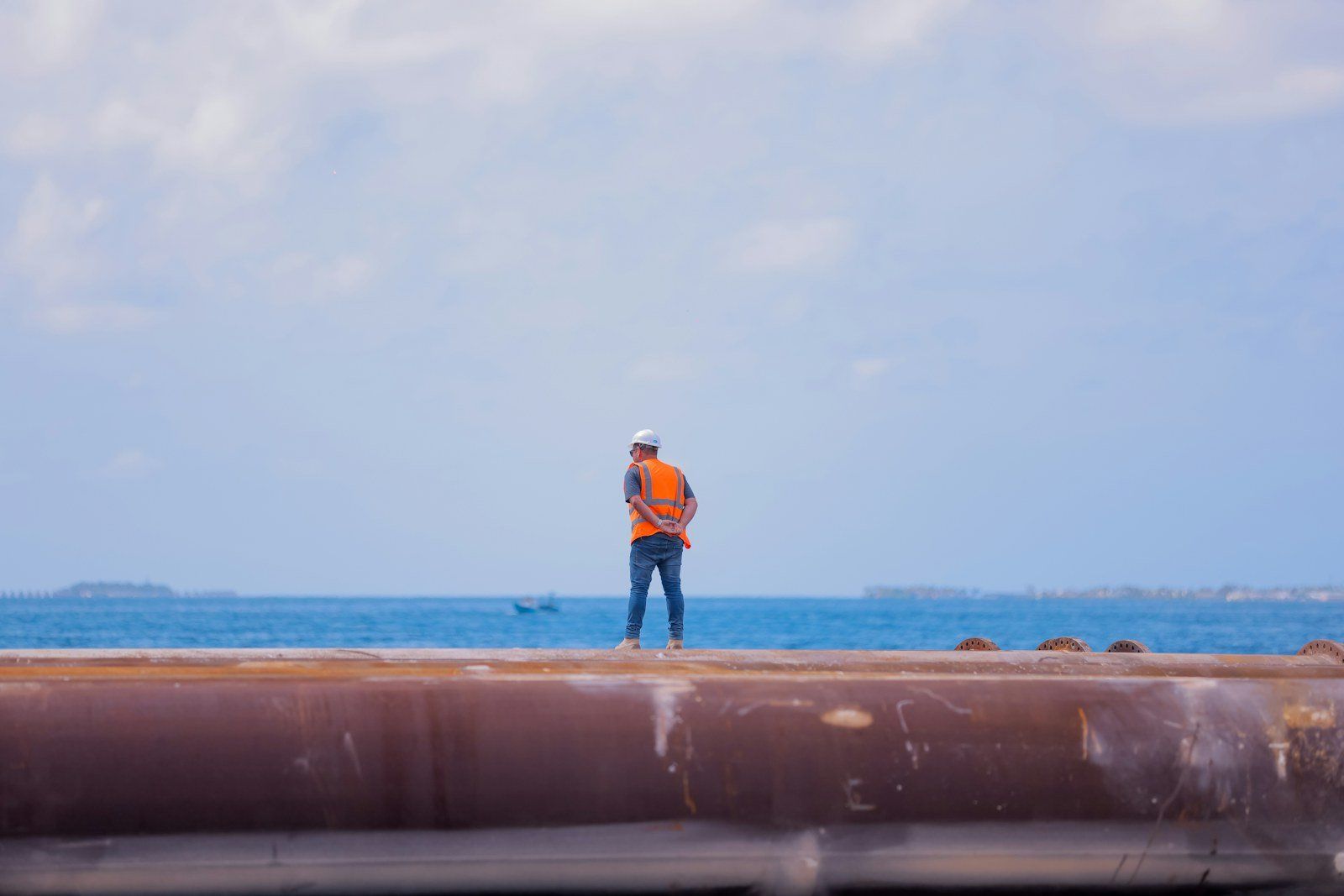 Field engineer in a hard hat and hi-vis vest on a coastal pipeline
