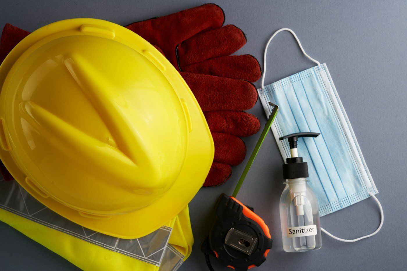 Yellow hard hat, work gloves, tape measure and PPE kit